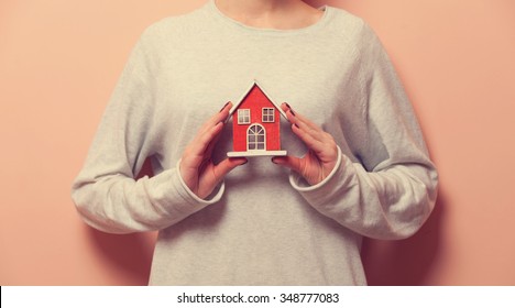 Woman Holding A Toy House On Pink Background