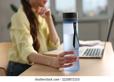 Woman holding transparent bottle at workplace indoors, closeup - Shutterstock ID 2220872153