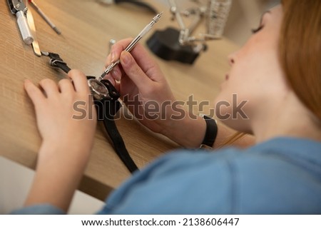 woman holding tweezers repairing vintage clocks