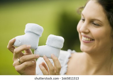 Woman Holding Up Two Baby Boots