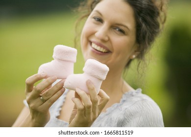 Woman Holding Up Two Baby Boots