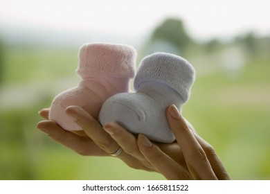 Woman Holding Up Two Baby Boots