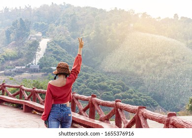 A Woman Holding Up Two Fingers At The Natural Forest At The Viewpoint At Sunrise In The Morning. A Symbol Of Peace And Victory Or Fighting.