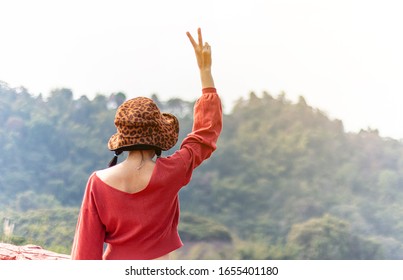 A Woman Holding Up Two Fingers At The Natural Forest At The Viewpoint At Sunrise In The Morning. A Symbol Of Peace And Victory Or Fighting.