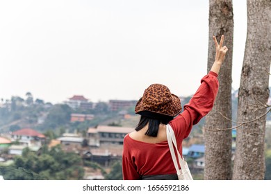 A Woman Holding Up Two Fingers At The Natural Forest At The Viewpoint At Sunrise In The Morning. A Symbol Of Peace And Victory Or Fighting.