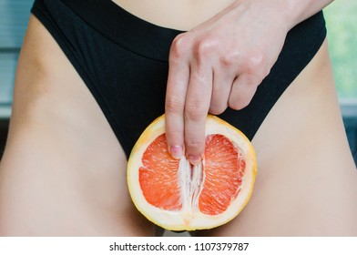 
A woman is holding Two fingers on grapefruit by her panties. Concept masturbation