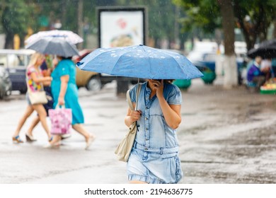 A Woman Is Holding An Umbrella During Heavy Rain In The City And Talking On The Phone.