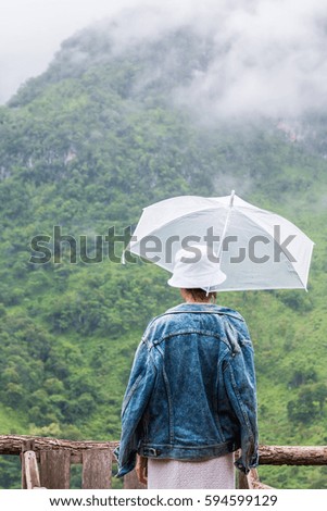 Woman holding an umbrella in the rain and fog.