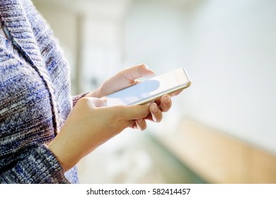 woman holding and using smartphone in corridor background. - Powered by Shutterstock