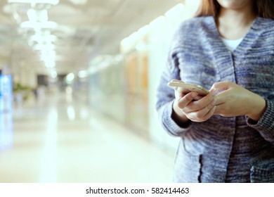 woman holding and using smartphone in corridor background. - Powered by Shutterstock