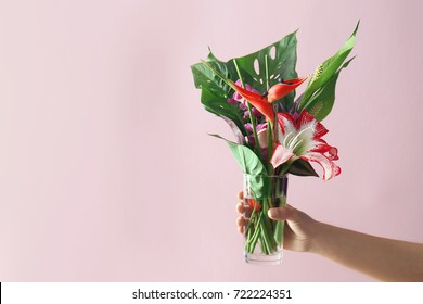 Woman Holding Vase With Beautiful Tropical Flowers On Color Background