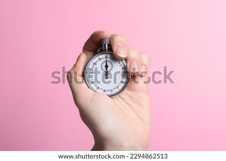 Woman holding vintage timer on pink background, closeup