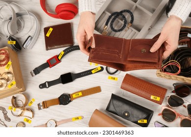Woman holding wallet near table with different stuff, top view. Garage sale - Shutterstock ID 2301469363