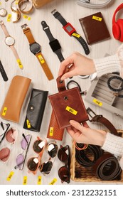 Woman holding wallet near table with different stuff, top view. Garage sale - Shutterstock ID 2312232151