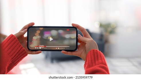 Woman holding and watching video via mobile phone in horizontal view at home. - Shutterstock ID 2135959779