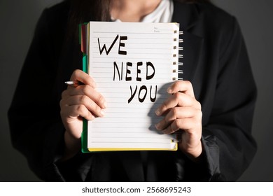 woman holding we need you text on notpead.