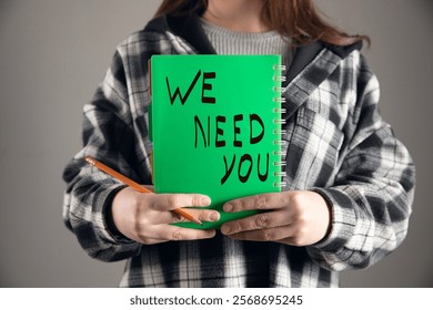 woman holding we need you text on notpead.