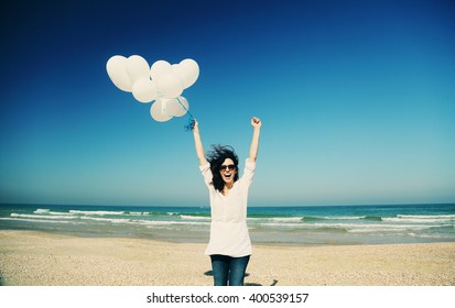 woman holding white balloons on seaside - Powered by Shutterstock