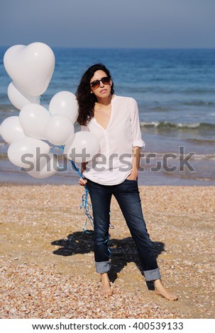 woman holding white balloons on seaside