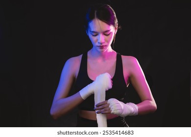 A woman is holding a white bandage in her hand. She is wearing a black tank top and she is in a contemplative mood - Powered by Shutterstock