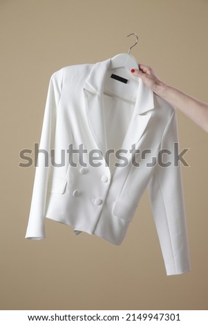 Woman holding white double breasted blazer on clothing hanger