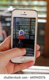 Woman Holding A White Iphone With Left Hand Playing Pokemon Go In A Bike Storage Room