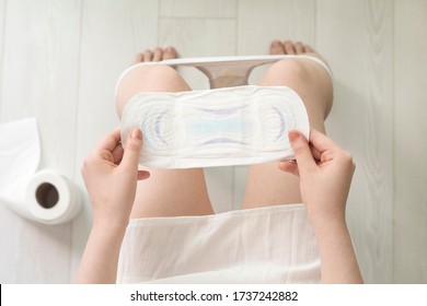 Woman Holding White Sanitary Pad In Toilet