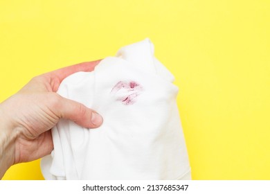 Woman holding a white shirt with red kiss lipstick on a yellow background. concept of treason and infidelity