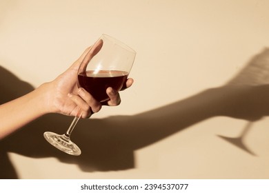 Woman holding a wine glass on orange background, in direct sunlight