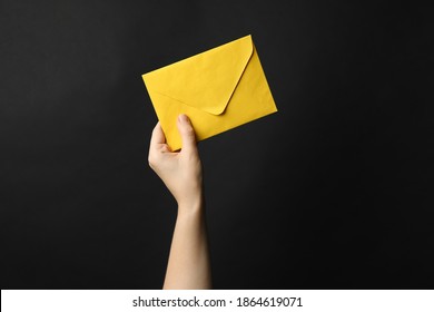 Woman Holding Yellow Paper Envelope On Black Background, Closeup