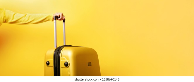 woman holding yellow suitcase in hand over yellow background, travel concept, panoramic mock up image