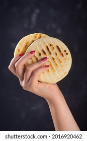 Woman Holds Arepa Is A Type Of Meal Made From Cornmeal, Traditional In The Cuisine Of Colombia And Venezuela, Dark Back