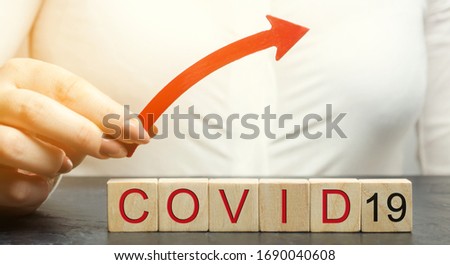 Woman holds up arrow over the word Covid-19. The concept of increased mortality and the diagnosis of new cases of coronavirus infection. Pandemic. Quarantine. Ncov