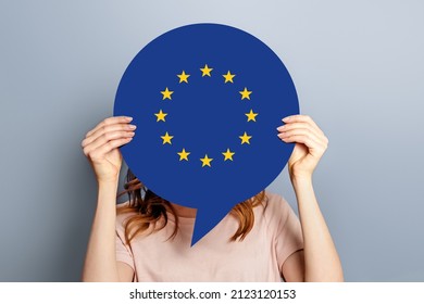 Woman Holds Blank White Speech Bubble With European Union Flag Isolated Over Grey Studio Background. News Information Channel Concept