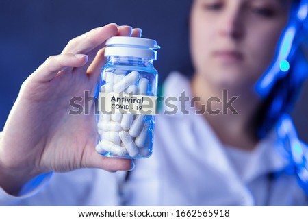 Woman holds box of antiviral medicines. Conception of  studies about coronavirus.