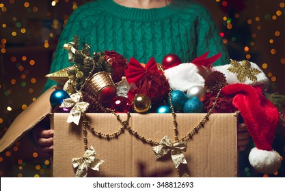 A Woman Holds A Box With A Lot Of Christmas Decorations