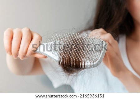 A woman holds a comb with a clump of hair in her hand. Close-up. The concept of alopecia and hair loss.