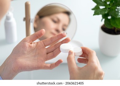 A woman holds a contact lens on her finger