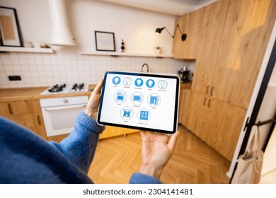 Woman holds a digital tablet with running smart home program, controlling smart kitchen appliances. Close-up on screen. Concept of new technologies for comfort living - Powered by Shutterstock