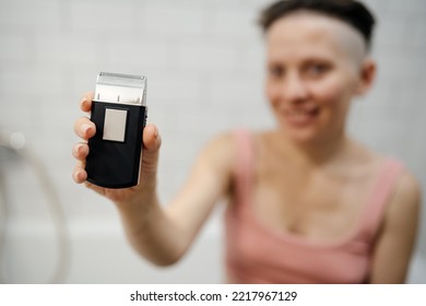 A Woman Holds An Electric Razor In Her Hand, A Shaver. Technologies For Beauty.