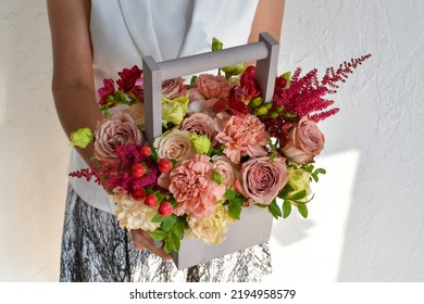 A Woman Holds Flowers In A Box In Her Hands. Photo For The Flower Catalog Of A Flower Shop. Fresh Fresh Flowers As A Gift