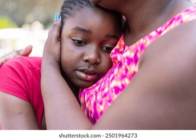 A woman holds a girl to her chest to console her - Powered by Shutterstock