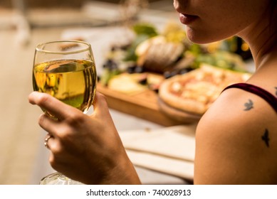 Woman holds glass of wine, pizza in background - Powered by Shutterstock