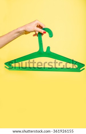 Woman holds green hanger over yellow background. No dress to wear concept