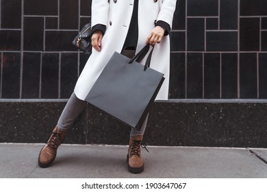 Woman holds in hand black shopping bag against black textured tile wall. Blank space, minimal brand package mock up concept, fashion blogger, space for text - Powered by Shutterstock