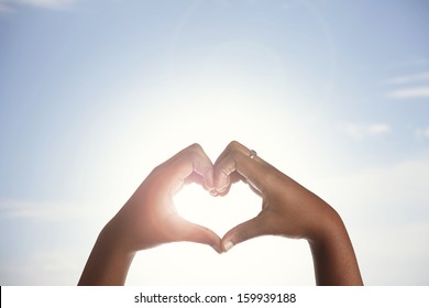 Woman Holds Hands Up To Sky In The Shape Of A Heart Around The Sun. 