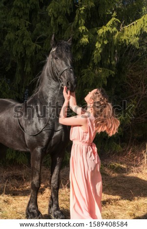 Woman holds her black horse in forest, outdoors photo. 