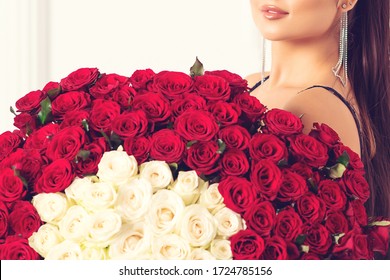 Woman holds luxury bouquet of red roses. Bouquet of hundred roses for a beloved woman. Love you. Celebration of engagement or wedding. Birthday gift. Happy Valentine's Day.