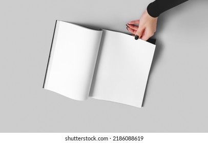 A Woman Holds A Magazine Or Catalog In A4 Format With White Sheets In Her Hand. Mockup With Place For Advertising.