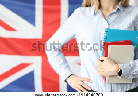 Woman holds notebooks and diaries against background of flags of Britain. Language courses and training concept